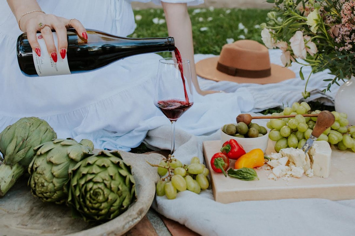 A hand holing a bottle of Willamette Valley Vineyards Wine over a charcuterie board